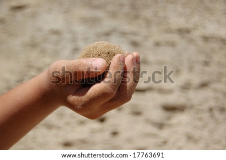 Small Child's hand holding wet sand ball
