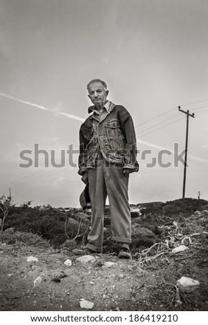 KARPATHOS, GREECE - OCTOBER 1, 2010: A peasant, in Karpathos, Greece, on October 1, 2010, stands on a field, while on work. Many residents of the island work with the harsh rocky land to survive.