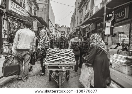 ISTANBUL, TURKEY - MAY 20, 2011: A man pushes his carriage full of bread rolls,among people, in a busy street, trying to sell them in order to make a living.