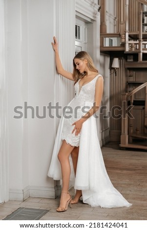 The beautiful woman posing in a wedding dress. Young beautiful happy bride wearing white wedding dress and posing in bright empty interior. Dress transformer, removable plume. Wedding fashion. Photo stock © 