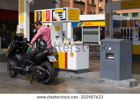 VALENCIA, SPAIN - JUNE 10, 2014: A man filling up his scooter at a Shell gas station in Valencia. According to Forbes, Royal Dutch Shell oil company is the 5th largest company worldwide.