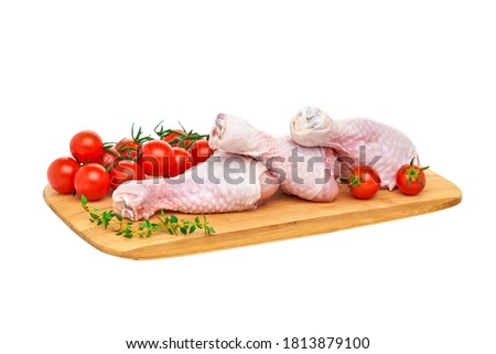 Three fresh raw chicken drumsticks on a wooden chopping Board with vegetables and herbs, on a white background. Close up. Stock fotó © 