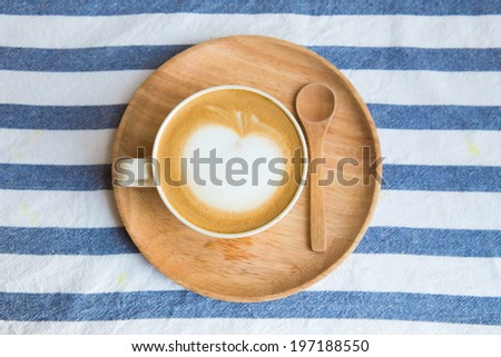 White cup of hot coffee latte on blue striped cloth
