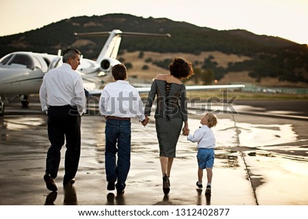 Family walking towards a private jet holding hands Imagine de stoc © 