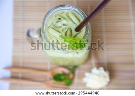 Ice green milk tea in big glass decorated with mint on wooden table