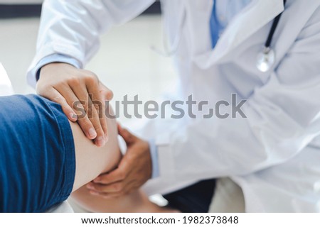 Professional orthopedist examining the little patient's leg in the clinic. Patient at the physiotherapy doing physical exercises with his therapist