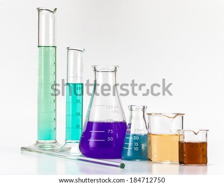 Various lab equipment, glass beakers, stirring rod, Erlenmeyer flasks filled with colored liquids