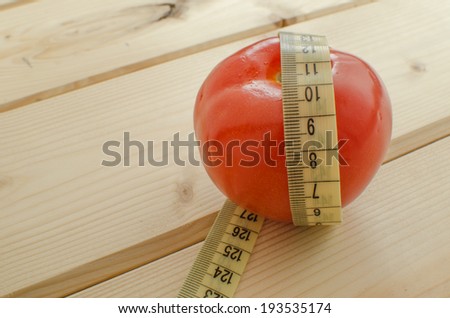 Simple picture of tomato with meter, on wood background