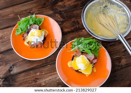 English muffin with bacon, egg benedict with hollandaise sauce and arugula salad