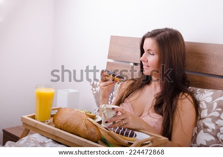 Beautiful young woman eating breakfast in bed in the morning, complete breakfast
