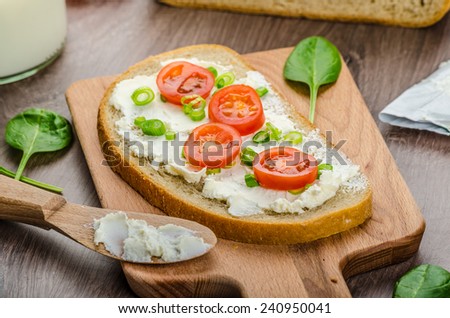 Fresh bread smeared with cream cheese, cherry tomatoes and spring onions, milk from farm