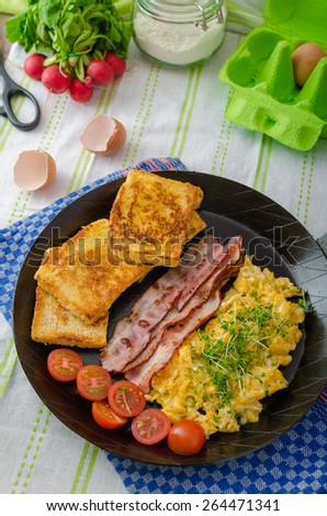 Scrambled eggs with bacon and French toast on a cast iron pan