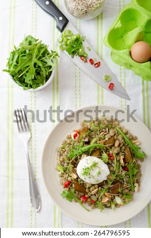 Healthy summer lentil salad with caramelized pear, arugula and poached egg soft on top