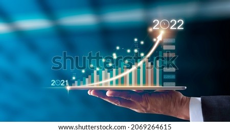 Businessman hand holding tablet showing graph economic growth target success from 2021 to 2022. Plans to increase business growth and Analysis strategy. Plan business growth in year 2022 concept.