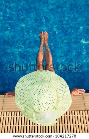 Woman in green hat resting in resort pool