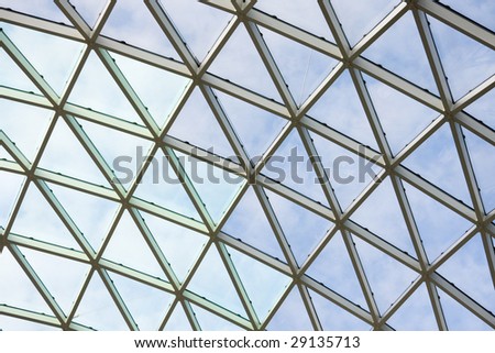 Transparent ceiling in modern office building. Blue sky with clouds in a background.