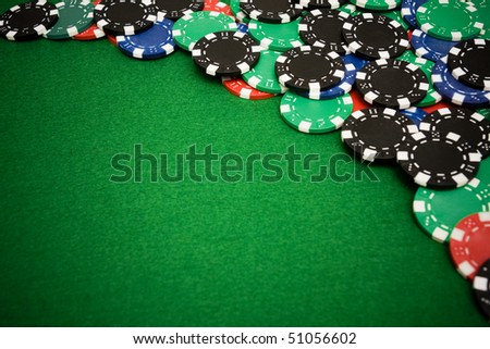 Colorful gambling chips on green felt background with copy space
