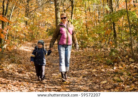 Mother and son taking a walk in autumn forest