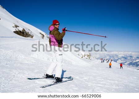 Woman in ski clothes pointing ski slope in alps mountains