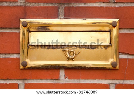 Old gold post box located on brick wall