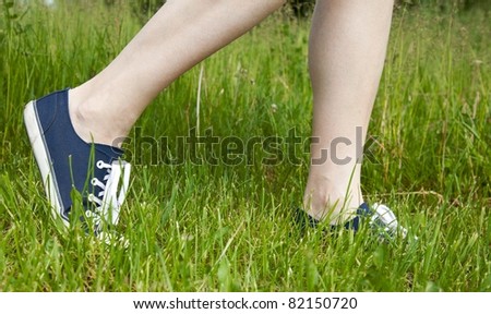 Woman walking on green grass in sport shoes