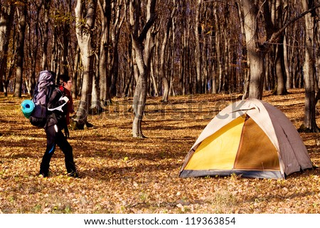 Happy female tourist in front of a camp tent or walking in the woods