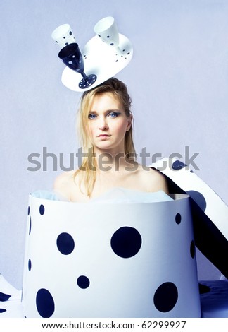 Young woman standing in a box with an interesting hat