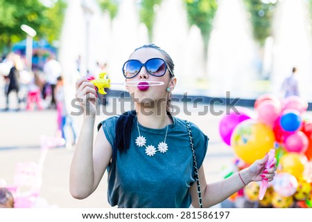 Young pretty girl blowing in a balloon soap maker