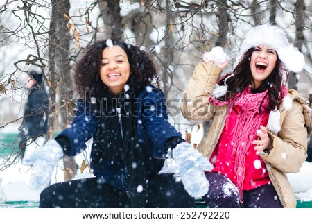 Two joyful and energetic friends playing games and having fun, having a snow ball fight in the snow mountains landscape during a skiing holiday on a sunny winter day, outdoors. snowballs