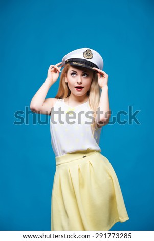 beautiful girl in the studio on a blue background in the style of pin-up, in a yellow dress, Dresses captain cap,\
Â  flirts