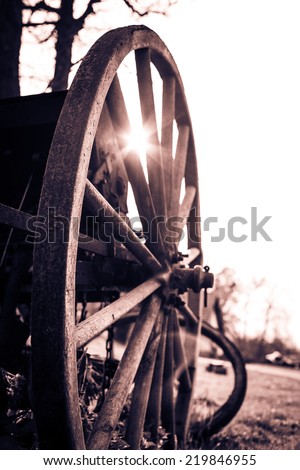 Close up of wooden wheel of an old coach at sunset. Color toned image. Cream tone. Sepia. Selective focus. Low depth of field.