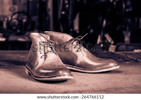 A pair of men\'s leather shoes in the shoemaker\'s workshop on working desk. Monochrome cream tone. Black and white photography.