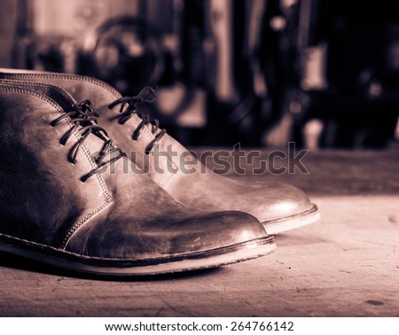 A pair of men\'s leather shoes in the shoemaker\'s workshop on working desk.Monochrome cream tone. Black and white photography.