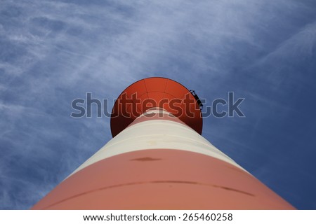 Modern red and white striped lighthouse on blue sky seen from an unusual wide angle directly from below. Rostock, Mecklenburg-Vorpommern, Germany