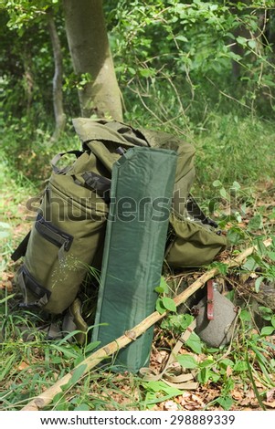 Backpack, camping mat and canteen in a forest.