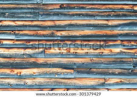 Weathered Barn Wall with Overlapped Gray and Brown Wood Siding in Rough Condition.