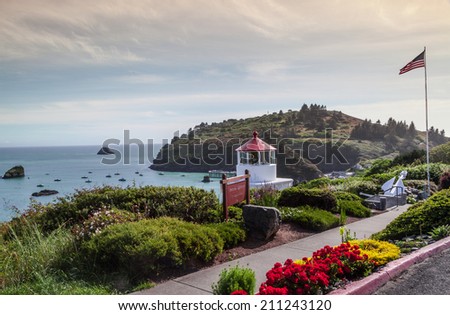 Memorial Lighthouse in Trinidad California, colorful flowers view and colorful bay and Little Head area, with the USA flag