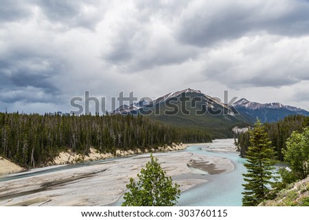 River and  clouds over the Rocky Mountain landscape. The Canadian Rockies have numerous high peaks and ranges. The Canadian Rockies are composed of shale and limestone