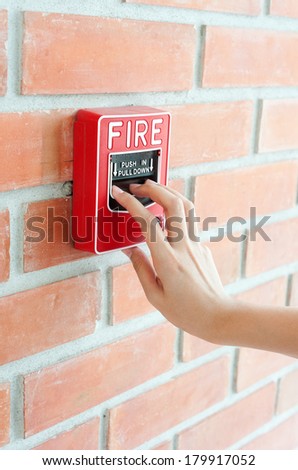 Hand pulling down the fire alarm button