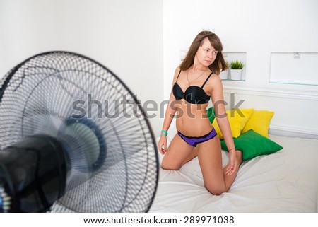 Sexy girl in lingerie cooling by fan in a hot day