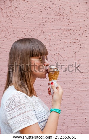 The girl in sunglasses eating ice cream on a pink background