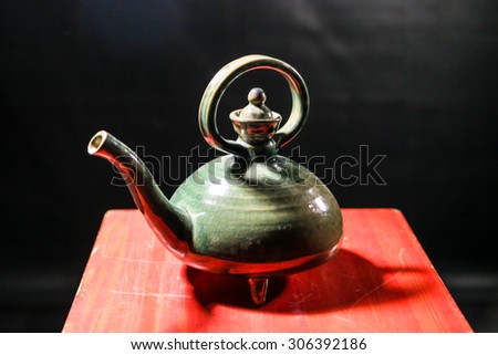 Green ceramic teapot on a red wooden background
