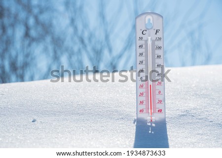 The thermometer lies on the snow and shows a negative temperature in cold weather on the blue sky.Meteorological conditions with low air and ambient temperatures.Climate change and global warming Foto stock © 