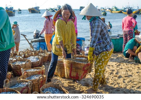 PHAN THIET, VIETNAM - JUL 17, 2013: Local women are transporting fish from their vessels to the local market.