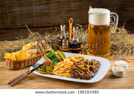 Roast beef, french fries and jug of beer on the rural table