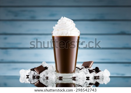 Iced coffee in glass and crushed ice on blue background