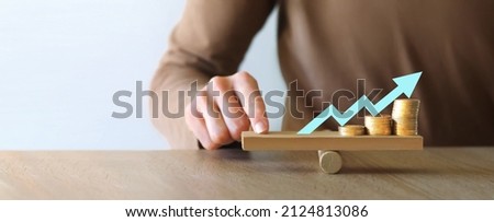 Money leverage and inflation balance. Businesswoman Balancing Stacked Coins With Finger On Wooden Seesaw. Financial concept Stock foto © 