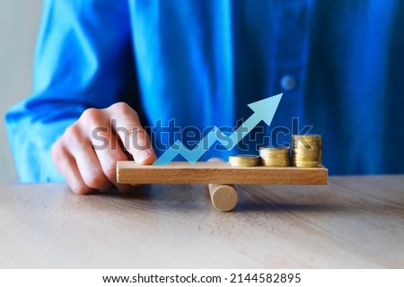 Money leverage and inflation balance. Business man Balancing Stacked Coins With Finger On Wooden Seesaw. Financial concept Stock foto © 