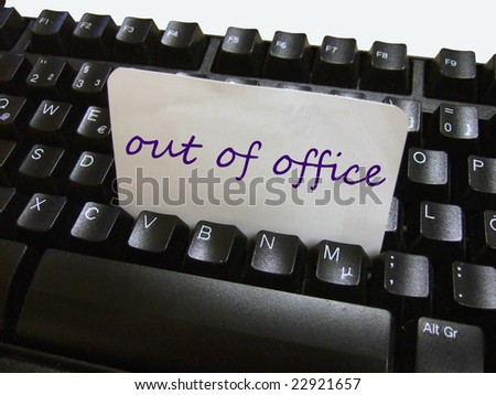 an out of office note on a piece of cardboard on the keyboard of an office work place