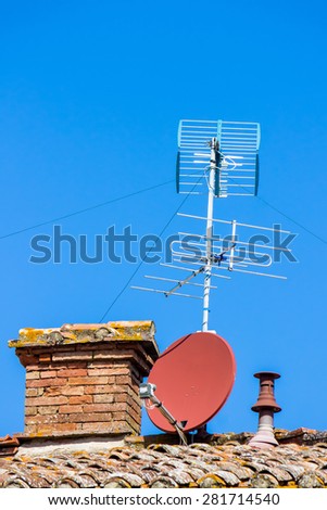 TV aerial and satellite dish on the roof with a blue sky in the background